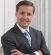 headshot image of Jonathan Waclawski in a dark suit, arms crossed, smiling at camera.