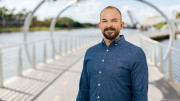 Photo of Steve Fiske in blue button down standing on river walk