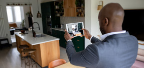 African American real estate agent taking pictures of a property with a tablet computer to list for sale