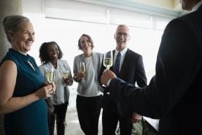 Happy business people celebrating, drinking champagne in conference room