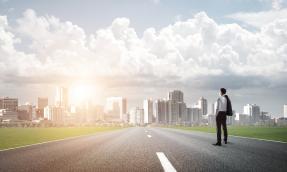 Man standing on highway looking at city in distance