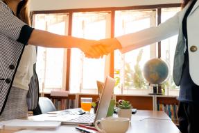 two women shaking hands in office