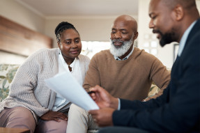 Agent showing documents to an older couple in their living room