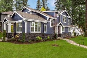 Blue-gray house green lawn pine trees