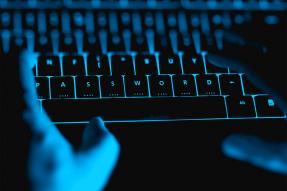 Blue-lighted hands and keyboard in the dark