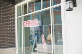 Business owners removing "Soon" from a "Coming Soon" sign