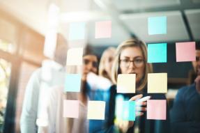 A group of businesspeople arranging sticky notes on a glass wall in a modern office