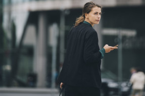 Businesswoman looking over shoulder while walking on street in city