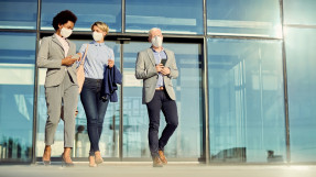 business coworkers with face masks talking while walking outdoors