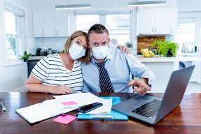 Stressed couple wearing masks in self-isolation over home finances and small business debts during quarentine