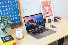 Desk with books, laptop, phone, headphones, and posters