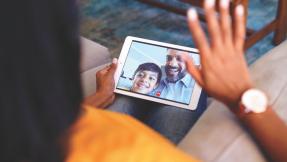 Woman waving at family from mobile tablet