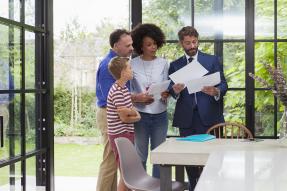 A family and a businessman looking at papers in a house