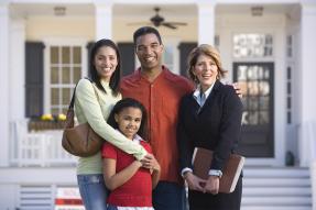 Family with agent in front of house