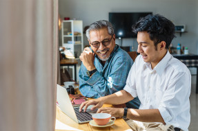 Father and adult son at laptop in home