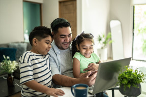 Father and two children at laptop in living room