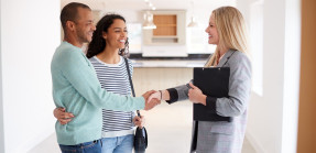 Real estate agent shaking hands with clients inside home