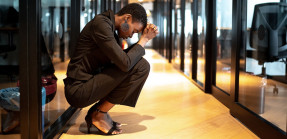 Businesswoman crouching in corner of office