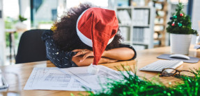 Woman wearing Santa hat and sleeping on desk