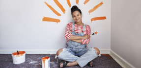 Woman sitting against wall with paint strokes around head