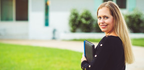 Smiling real estate appraiser with notebook in front of house