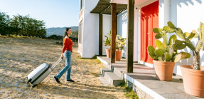 woman with luggage walking up to house