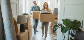 Older couple carrying boxes into home