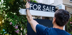 Real Estate Agent Adjusts For Sale Sign in Front Yard