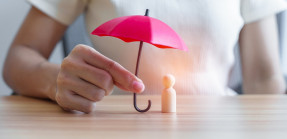 Person holding umbrella over figurine