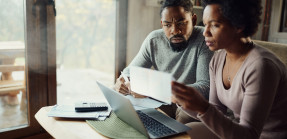 Black couple paying bills on computer at home