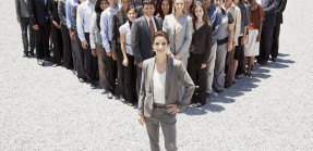 Confident businesswoman with team of business people in background