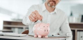 Man putting coin into piggy bank