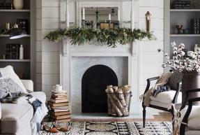 A green garland hangs over a white marble fireplace.