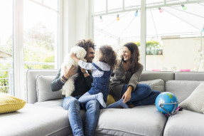 Happy family with dog sitting together in cozy living room