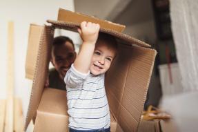 Little boy playing with moving box; father watching