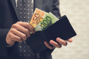 Man in a suit taking euros out of wallet