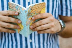 Man wearing a blue and white striped shirt and holding a book with a map cover