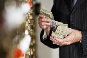 A man in a suit holding a handful of currency bills