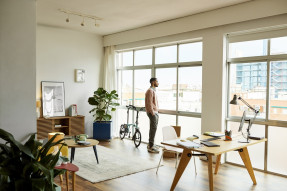 Young man looking out the glass window in his home office