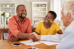 Man with white hair with clients, shaking hands