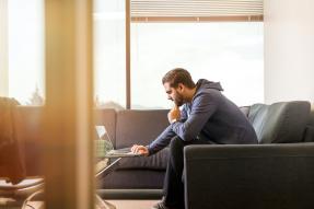 Man in his living room working on a laptop