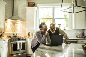 Older couple looking at a laptop on a kitchen island