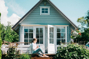 Woman sitting outside at deck in the back of a house