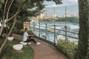 A man sitting in a park overlooking a stadium