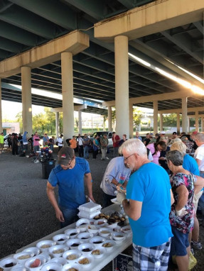 Volunteers serve the homeless under a bridge