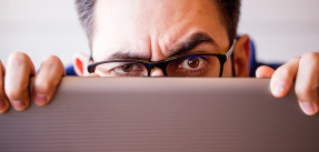 Man peering over laptop