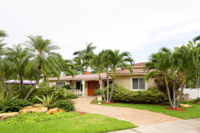 Spanish style single level home with palm trees in yard