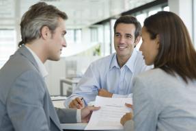 Three people at a desk with a contract