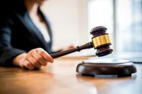 Close-Up Of Woman Holding Gavel On Table