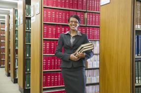 Woman in a suit holding books in a law library